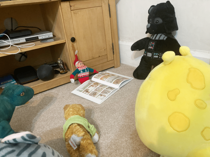 elf reading a children’s Christmas book to toys