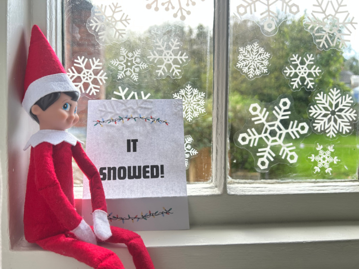 elf on the shelf with snowflake stickers on a window