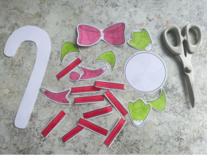 Cut out candy cane craft template pieces with scissors to build a candy cane