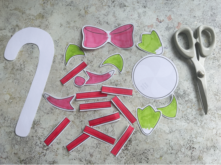 Cut out candy cane craft template pieces with scissors to build a candy cane