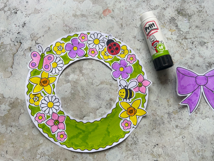 Gluing flowers and bee onto a spring wreath craft for kids