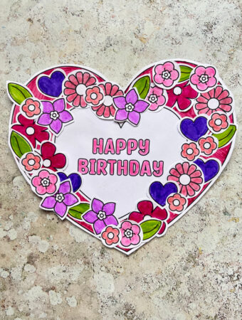 Printable birthday wreath craft made with a paper wreath and heart and flower decorations