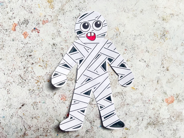 assembling halloween mummy craft stuck on eyes, mouth and head