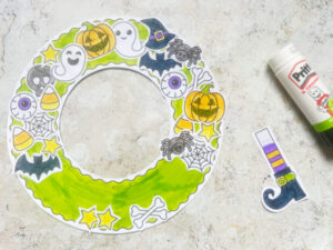Assembling the Halloween wreath craft gluing pumpkins, bats and ghosts onto it