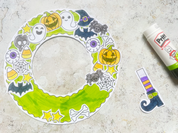 Assembling the Halloween wreath craft gluing pumpkins, bats and ghosts onto it