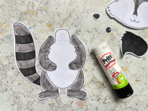 assembling the raccoon craft gluing on arms, legs and tail