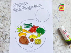assembling the thanksgiving dinner craft by gluing food onto the plate